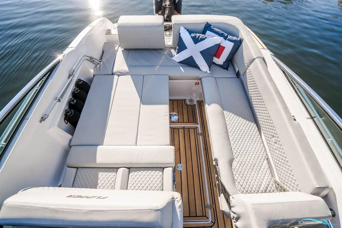 Luxury boat interior with plush seating, wooden flooring, and decorative cushions, reflecting on calm water.